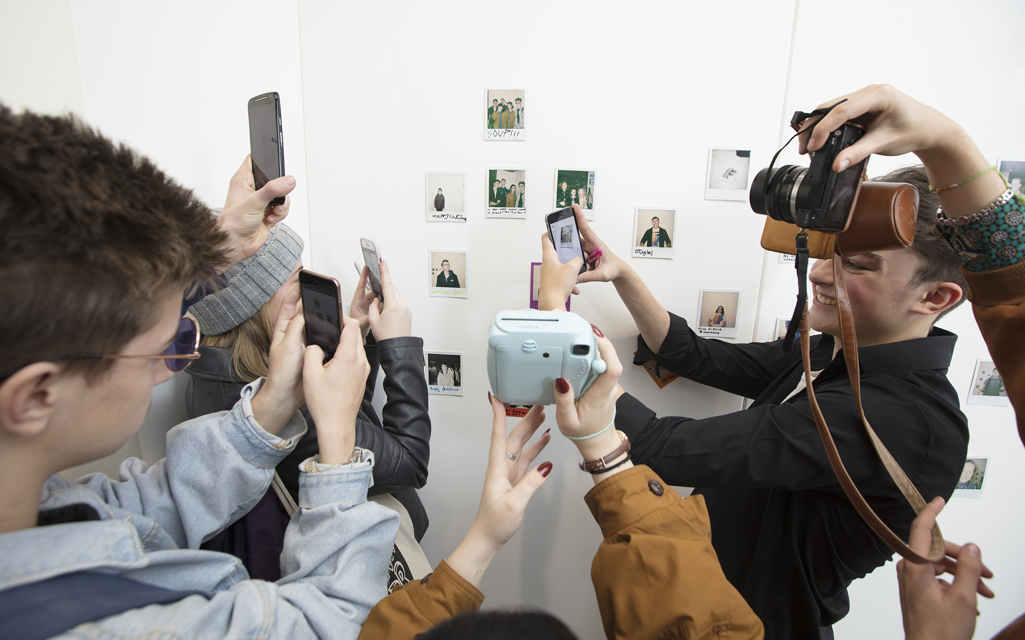 Young people hold phones and cameras to take photos