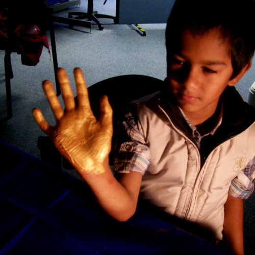 Child holding up hand with palm painted bronze