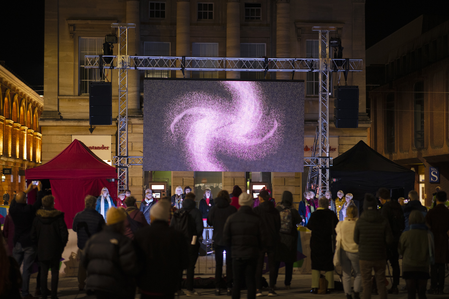 Crowd of people watching a performance and large screen with visuals
