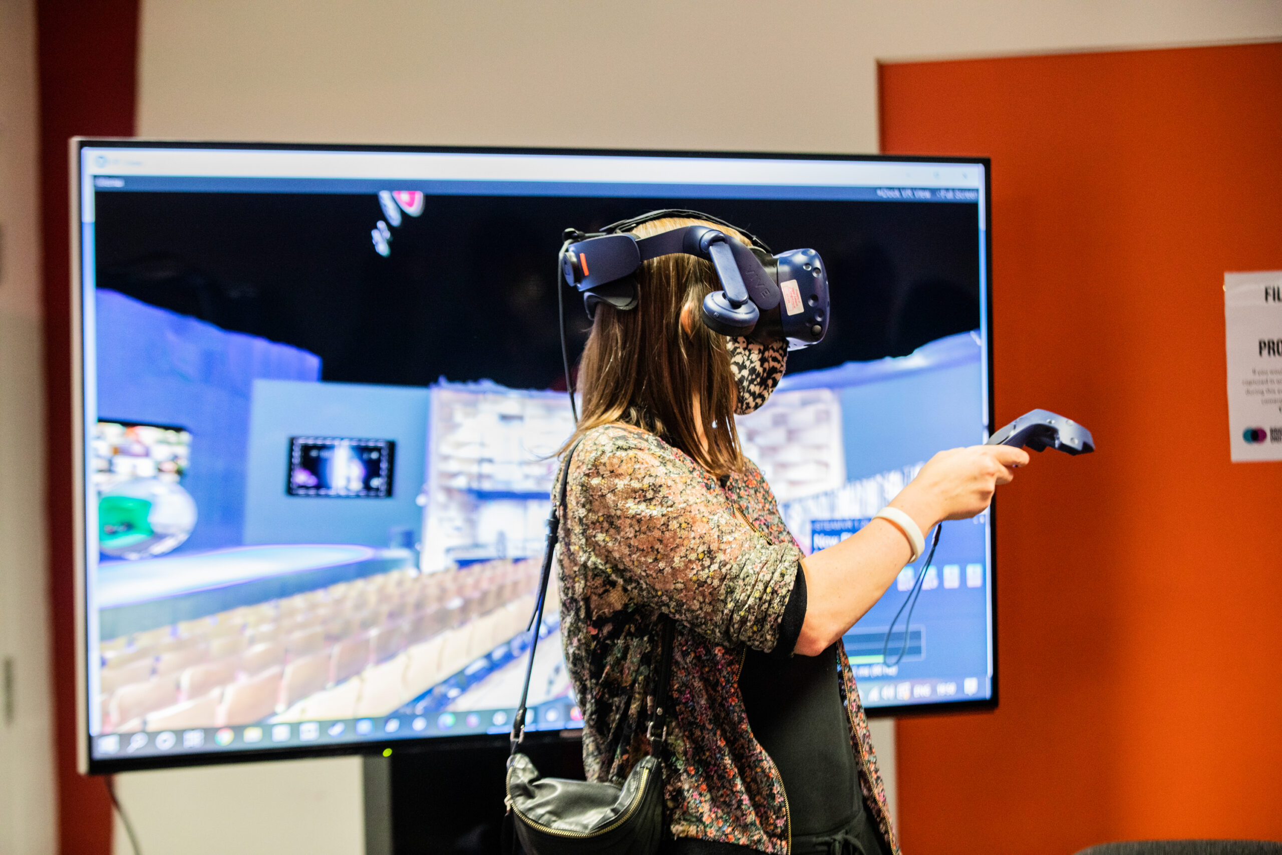 woman wearing vr headset in front of a screen with a virtual world