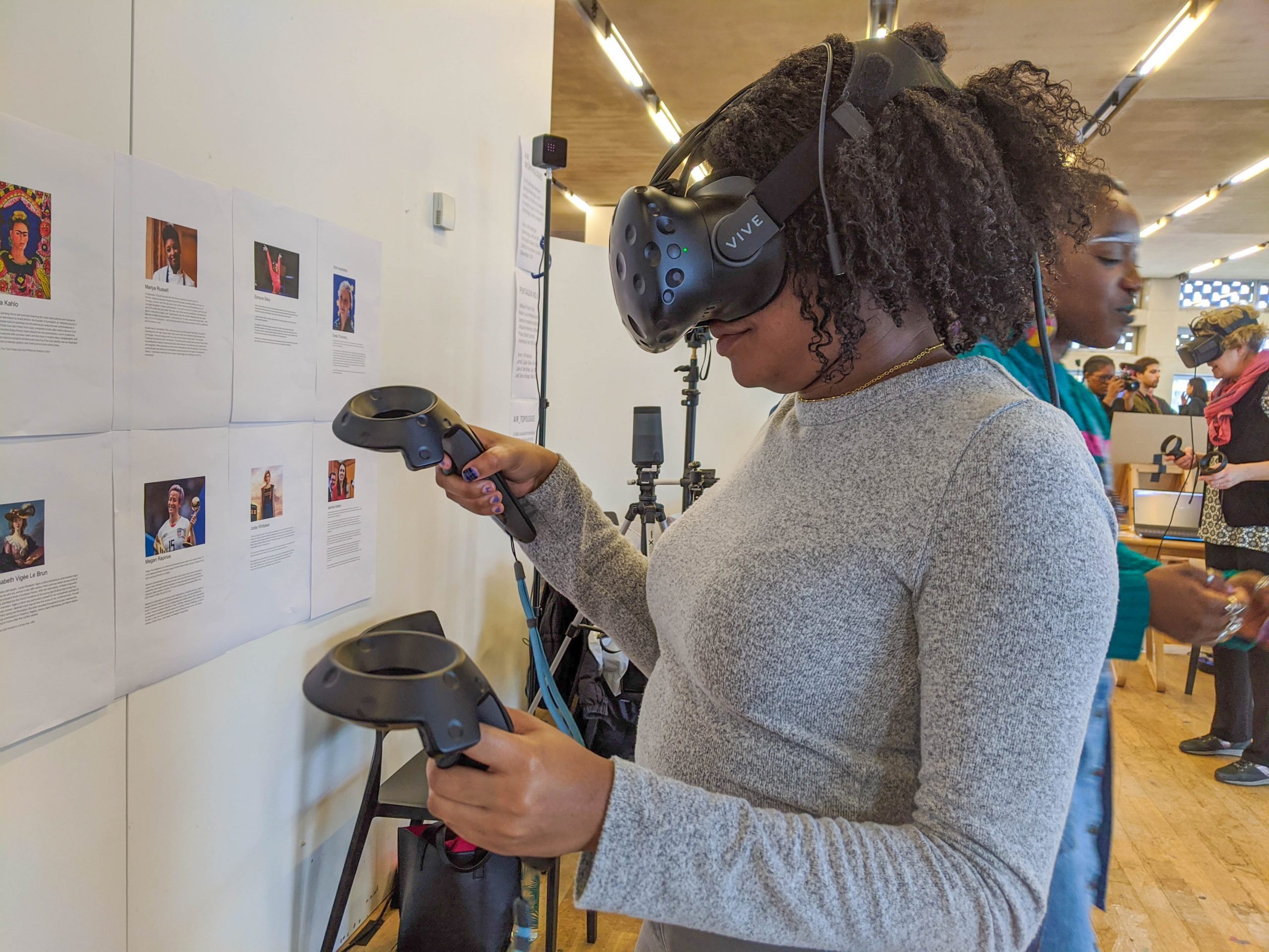 black woman wearing VR headset and holding controllers in front of a wall of images